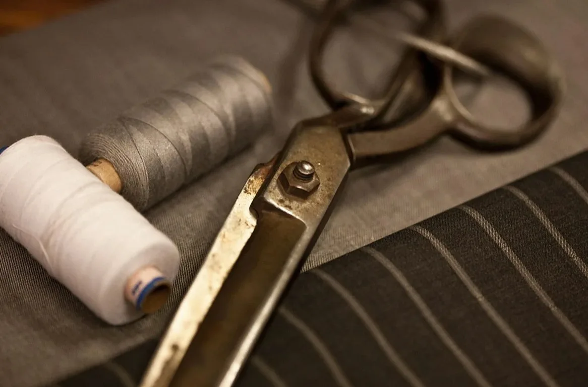 Scissors and spools of thread on grey pinstripe fabric
