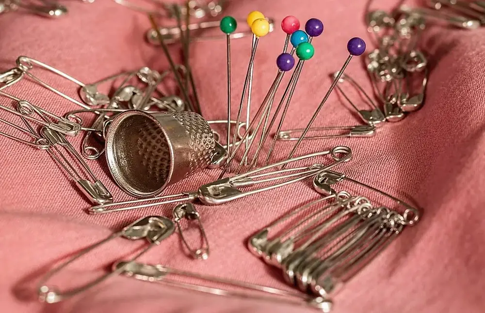 Pins, a thimble and safety pins on pink fabric