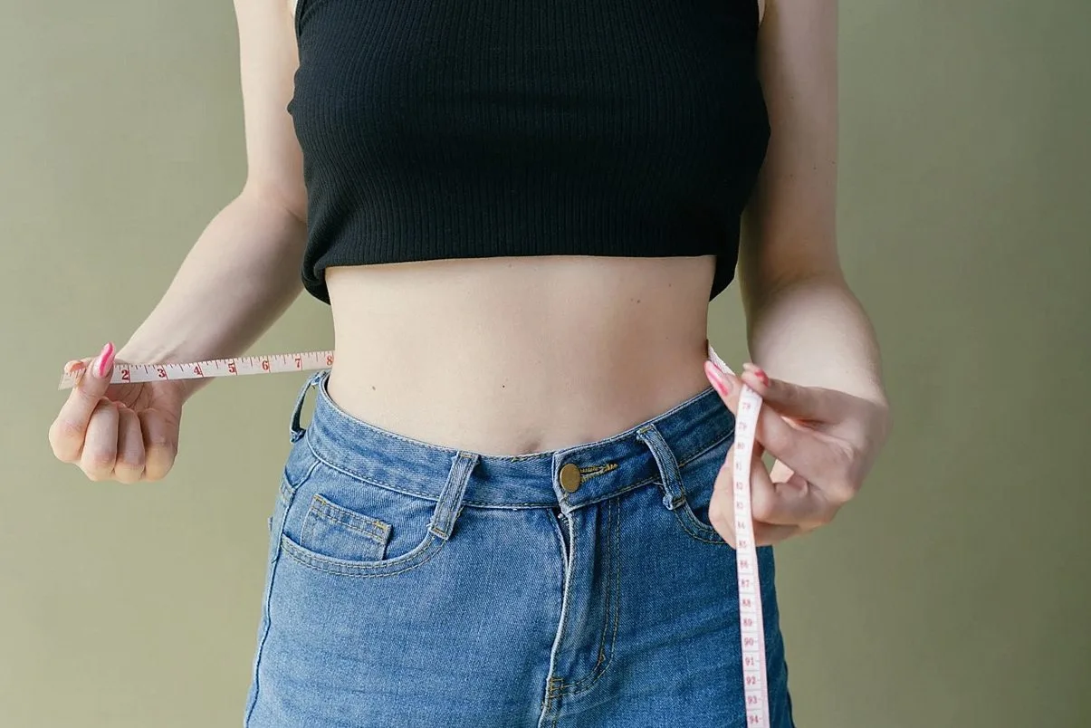 Woman measuring her waist with a soft tape measure