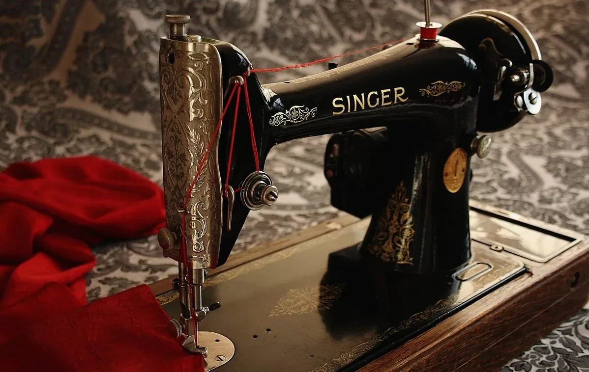 Black antique sewing machine beside red fabric