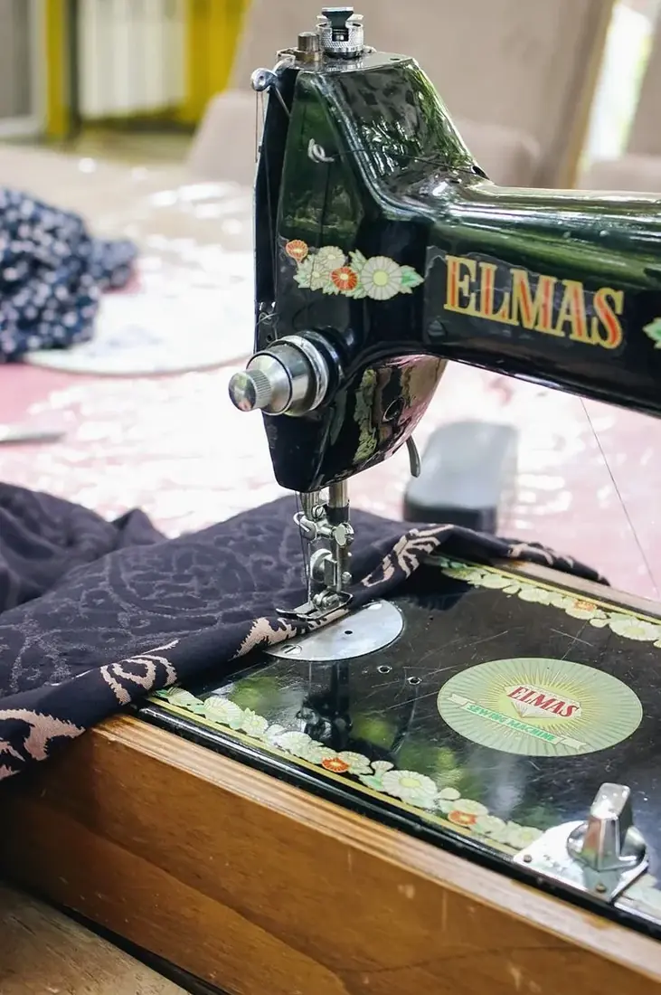 Vintage sewing machine stitching dark floral fabric