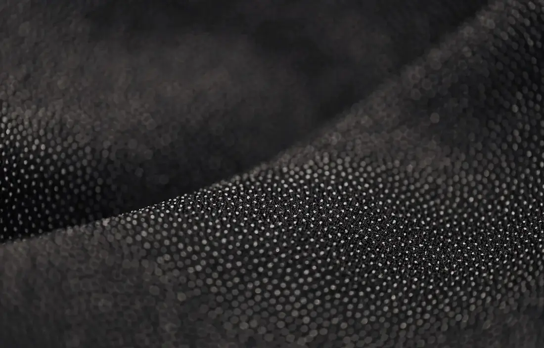 Close-up of dark stretch fabric with a fine dotted texture